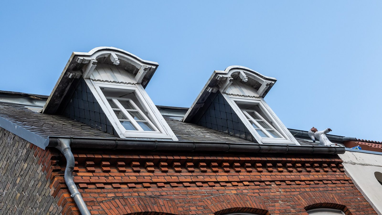 Dakkapellen met een dakgoot en regenpijp aan een woning