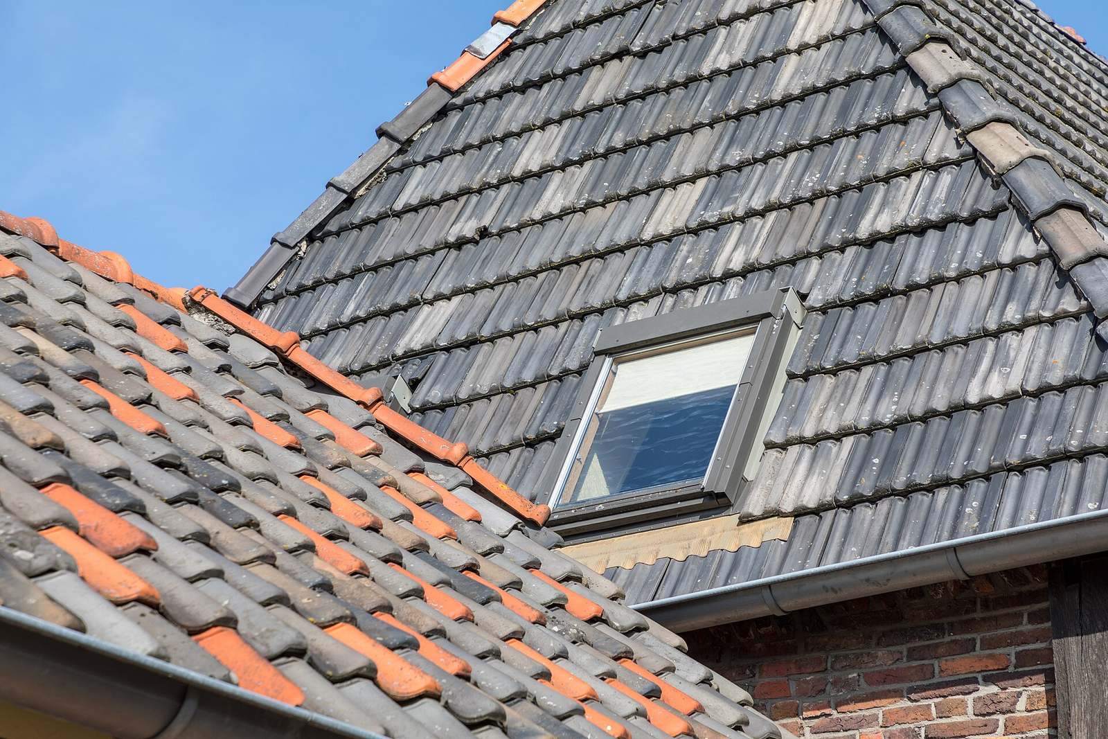 Dak met oranje en grijze dakpannen en een dakraam